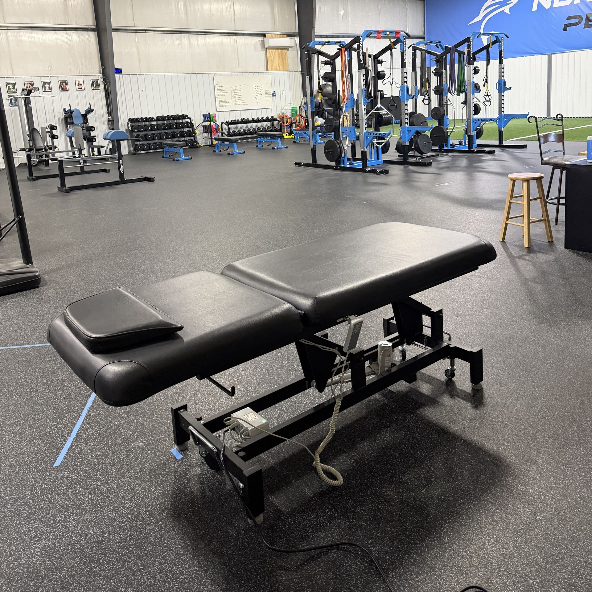 Massage table in a gym with weight racks and a 