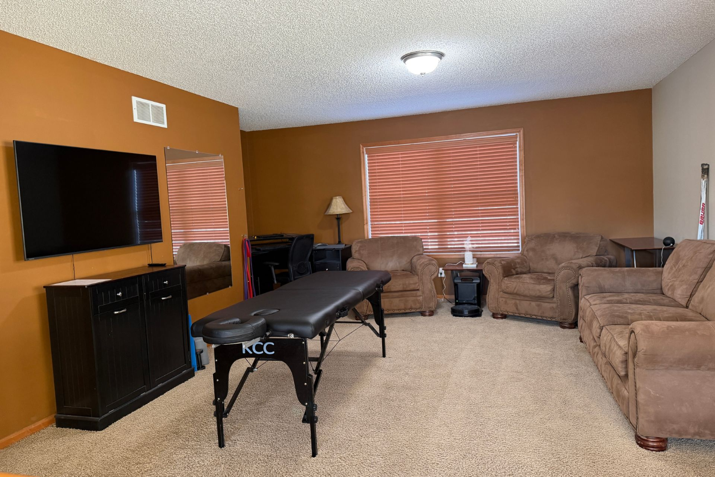 Massage therapy room with brown walls, furniture, and a window.