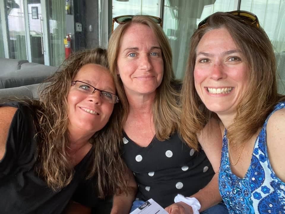 Three women are posing for a picture together and smiling for the camera.