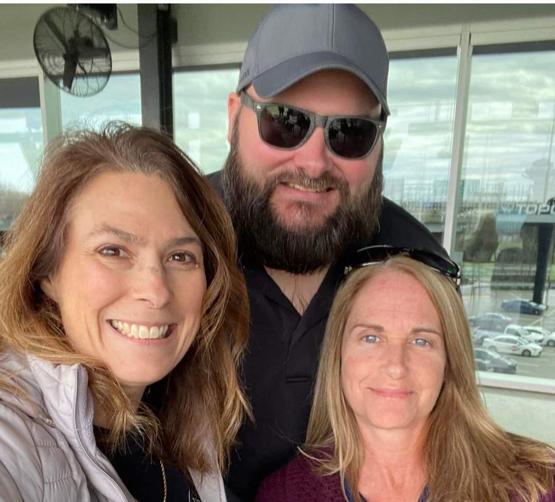 A man with a beard is posing for a picture with two women.