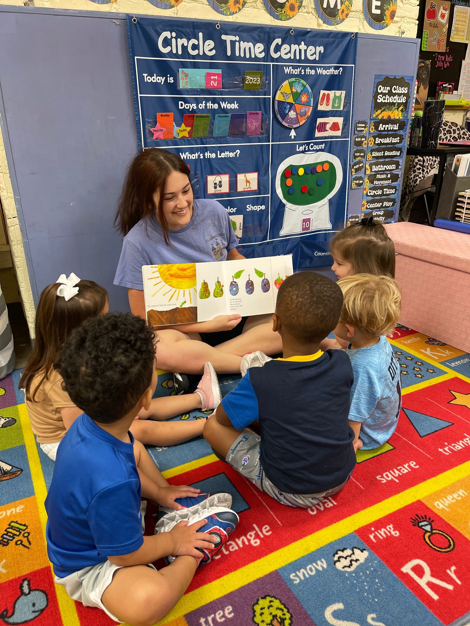 a woman is reading a book to a group of children .