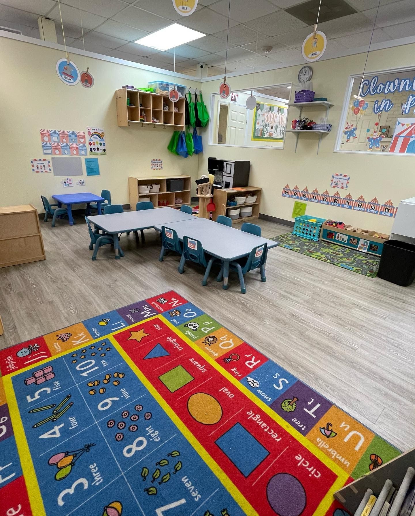 a classroom with tables and chairs and a colorful rug .