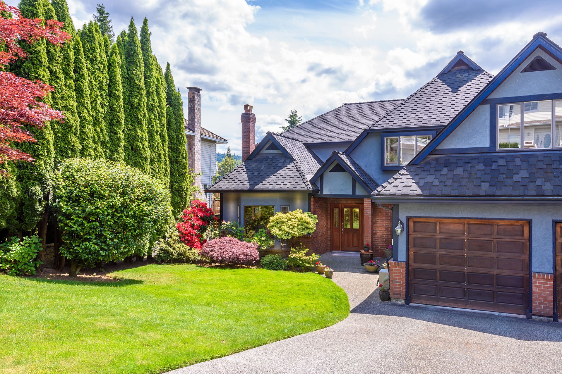 A large house with a large driveway and a large lawn in front of it.
