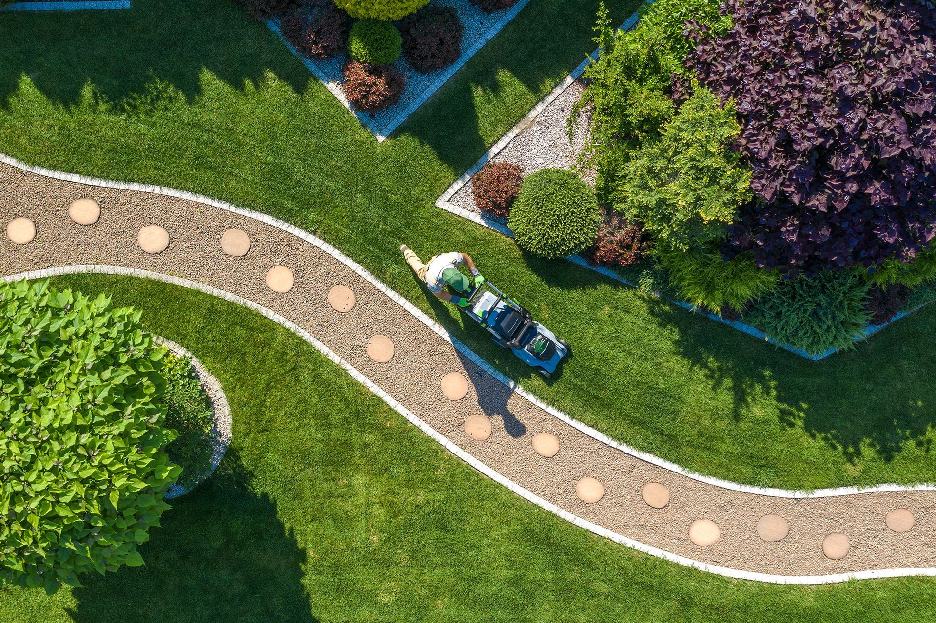 An aerial view of a person cutting grass in a garden.
