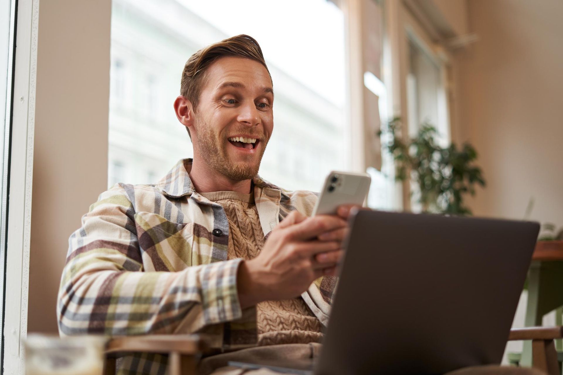 Brand & Flair Website Design - A man is sitting at a table using a laptop and a cell phone.