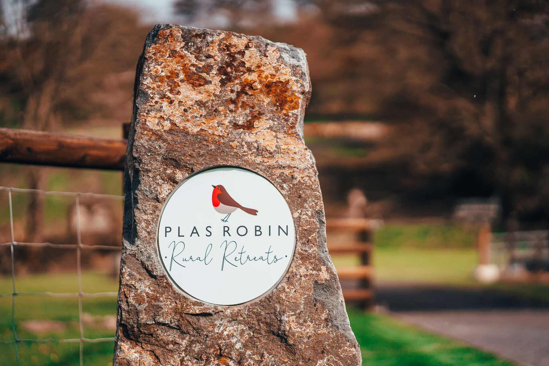 A large rock with a sign on it that says plas robin road retreats