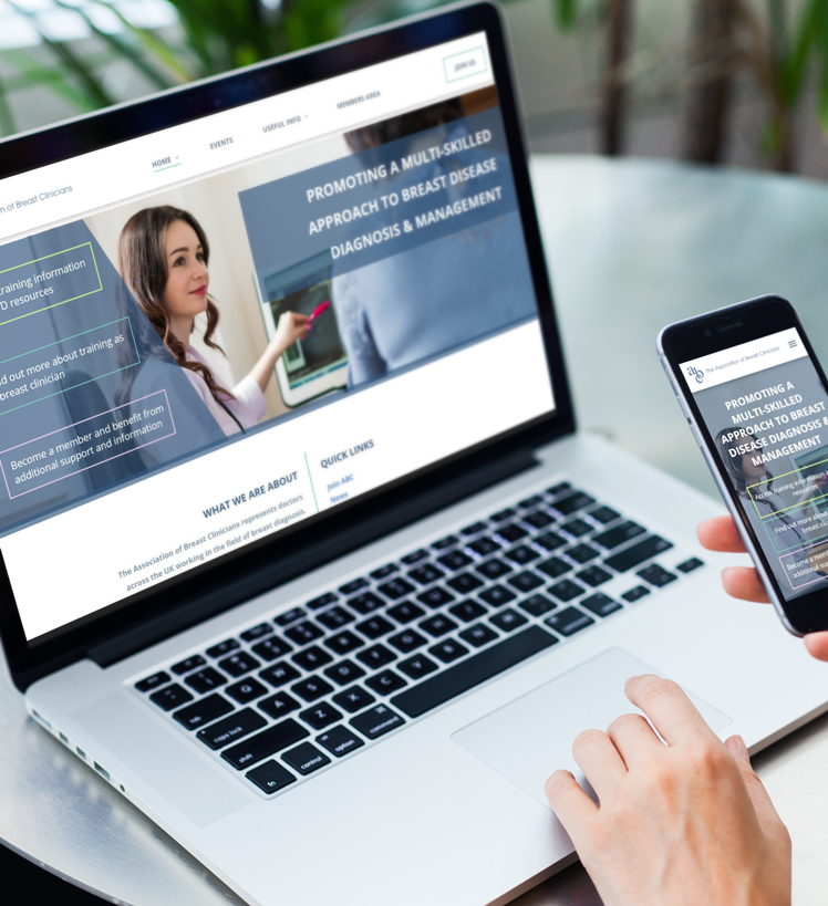 A person is holding a cell phone in front of a laptop