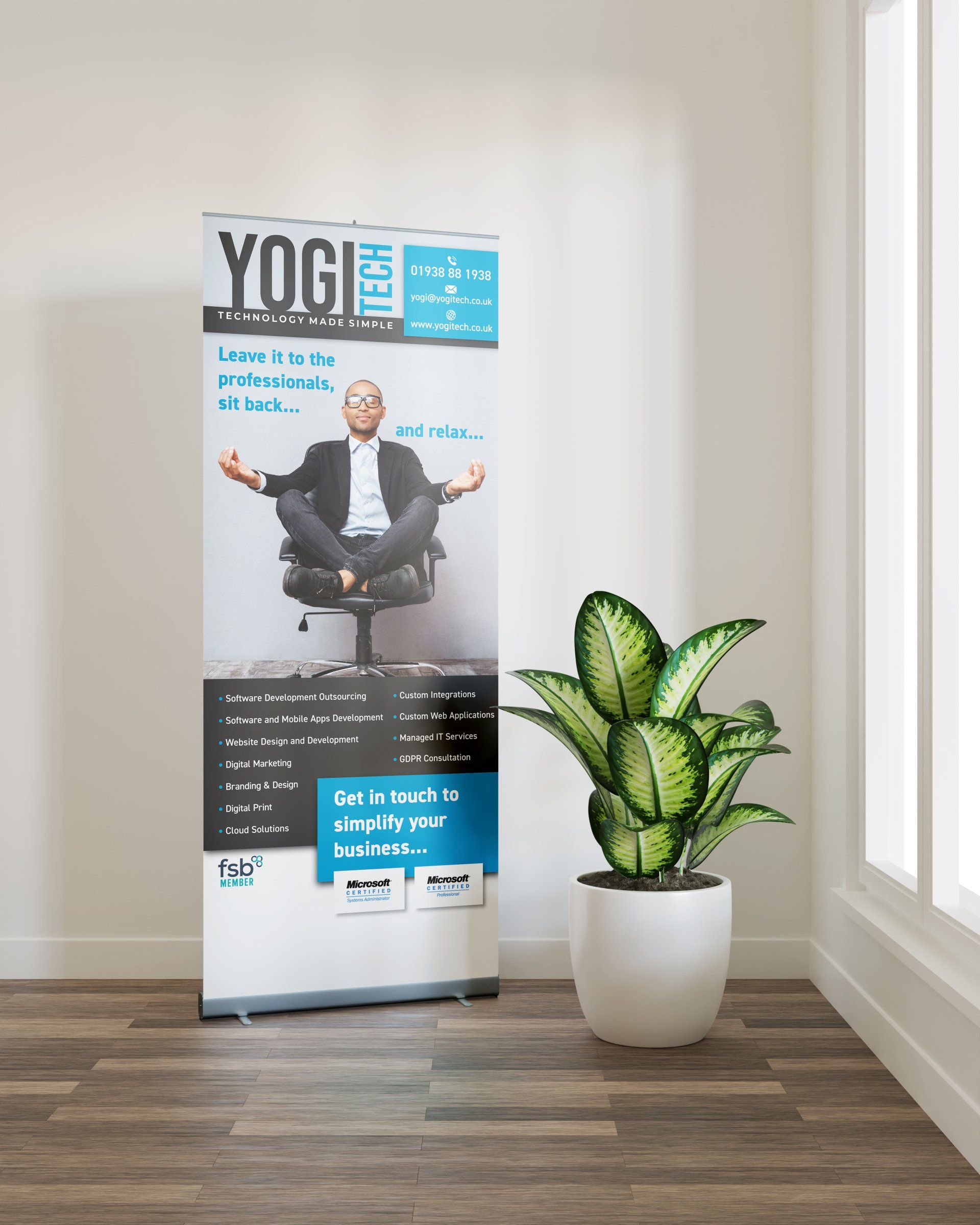 A man in a suit sits in a chair next to a plant and a sign that says yogi
