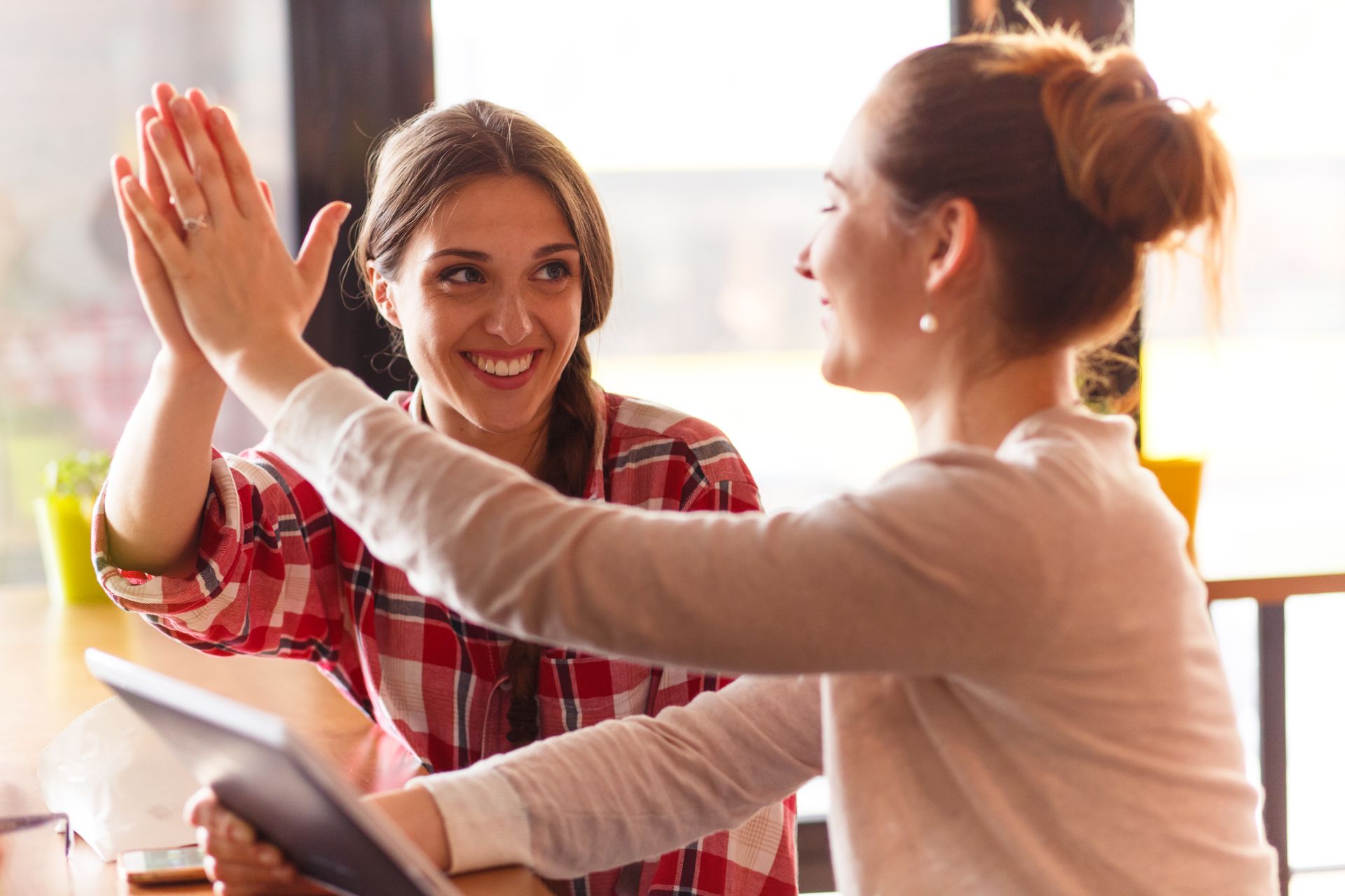 Brand & Flair Website Design - Two women are giving each other a high five while sitting at a table.