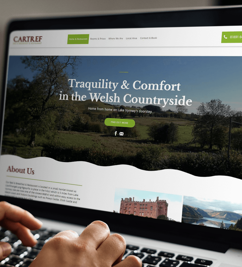 A person is typing on a laptop that says tranquility & comfort in the welsh countryside