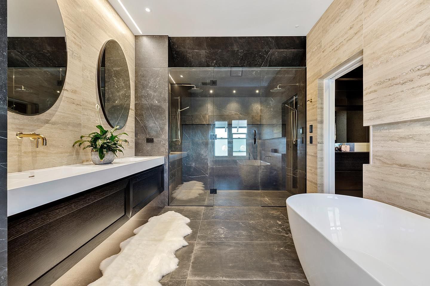 A bathroom with a bathtub , sink , mirrors and a walk in shower.