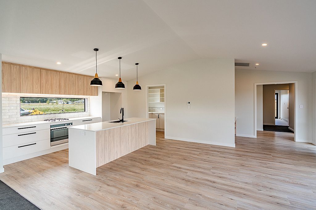 An empty kitchen with a wooden floor and white cabinets.