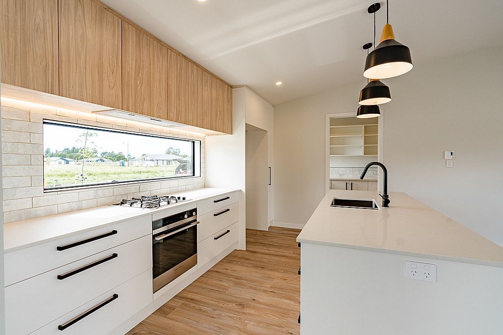 A kitchen with white cabinets , stainless steel appliances , a sink , and a window.