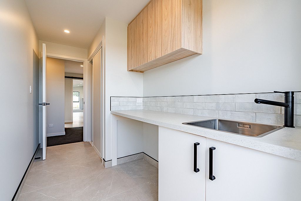 An empty kitchen with white cabinets and a sink.