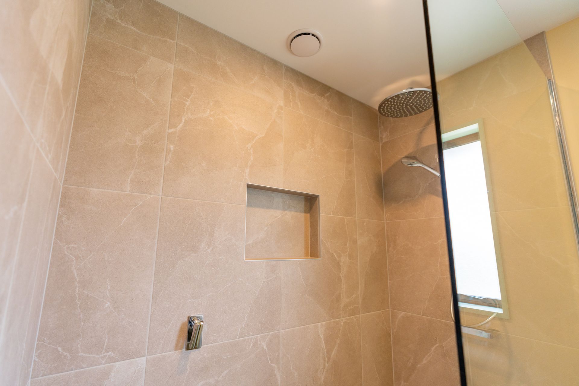 A bathroom with a walk in shower and a window.