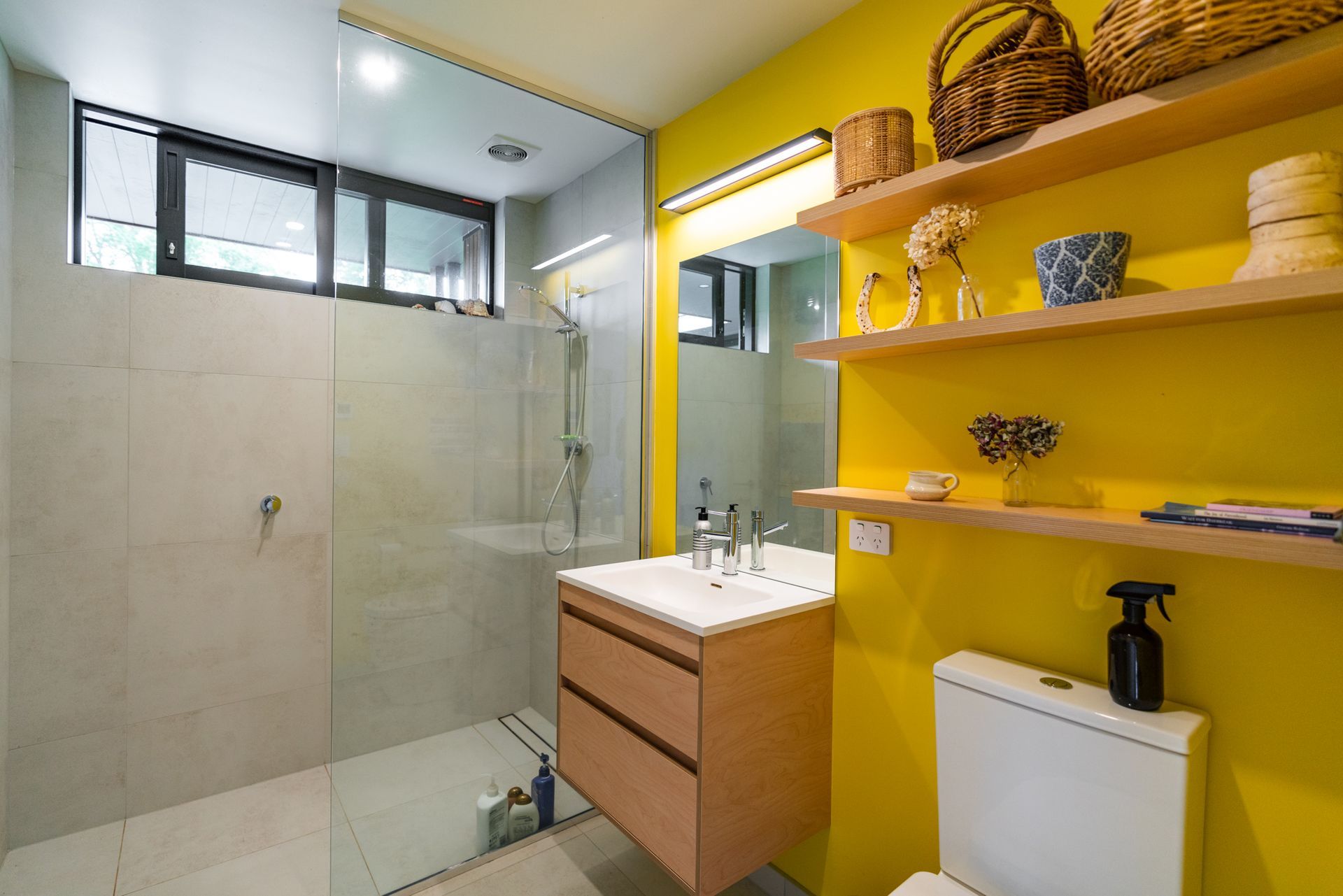 A bathroom with yellow walls , a sink , toilet and shower.