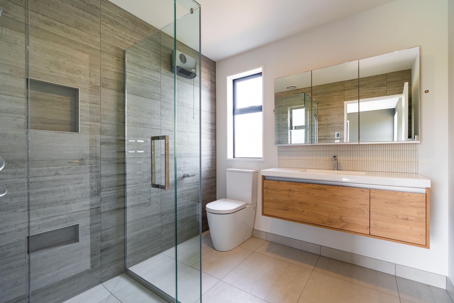 A bathroom with a walk in shower , toilet , sink and mirror.