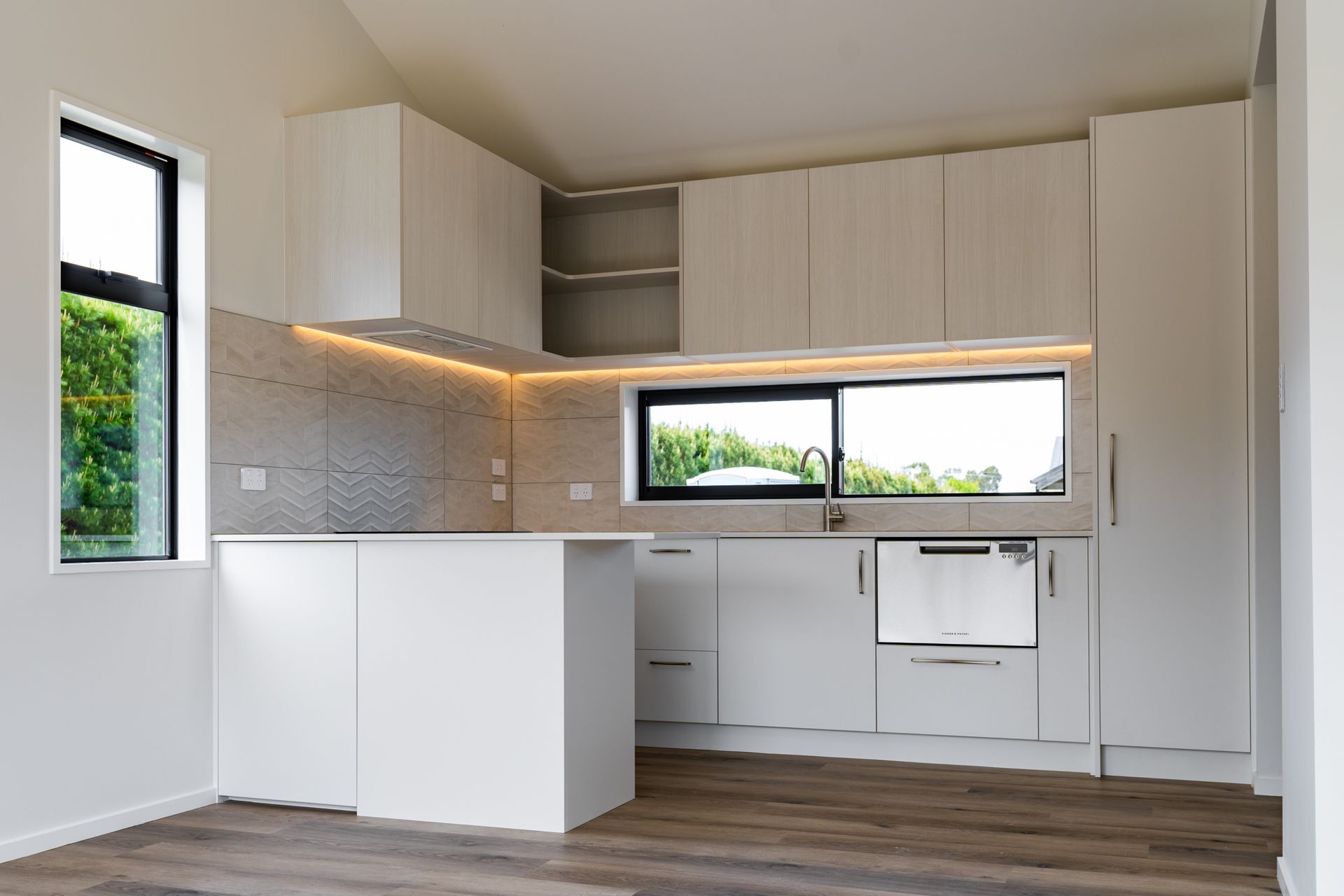 An empty kitchen with white cabinets and stainless steel appliances