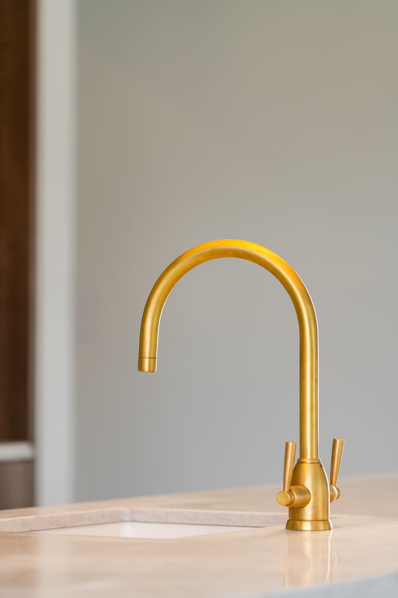 A close up of a gold faucet on a kitchen counter.