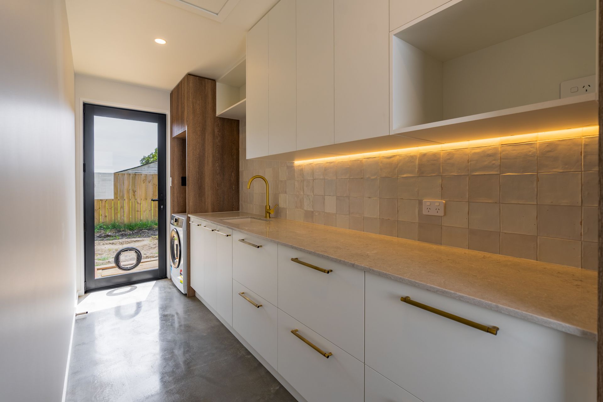 A kitchen with white cabinets and a sliding glass door.