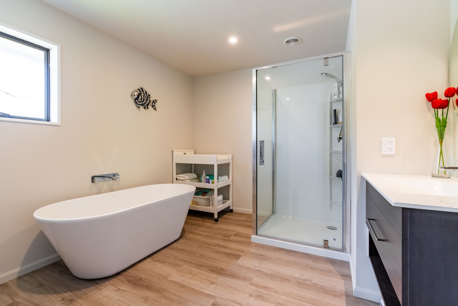 A bathroom with a bathtub , sink , shower and window.