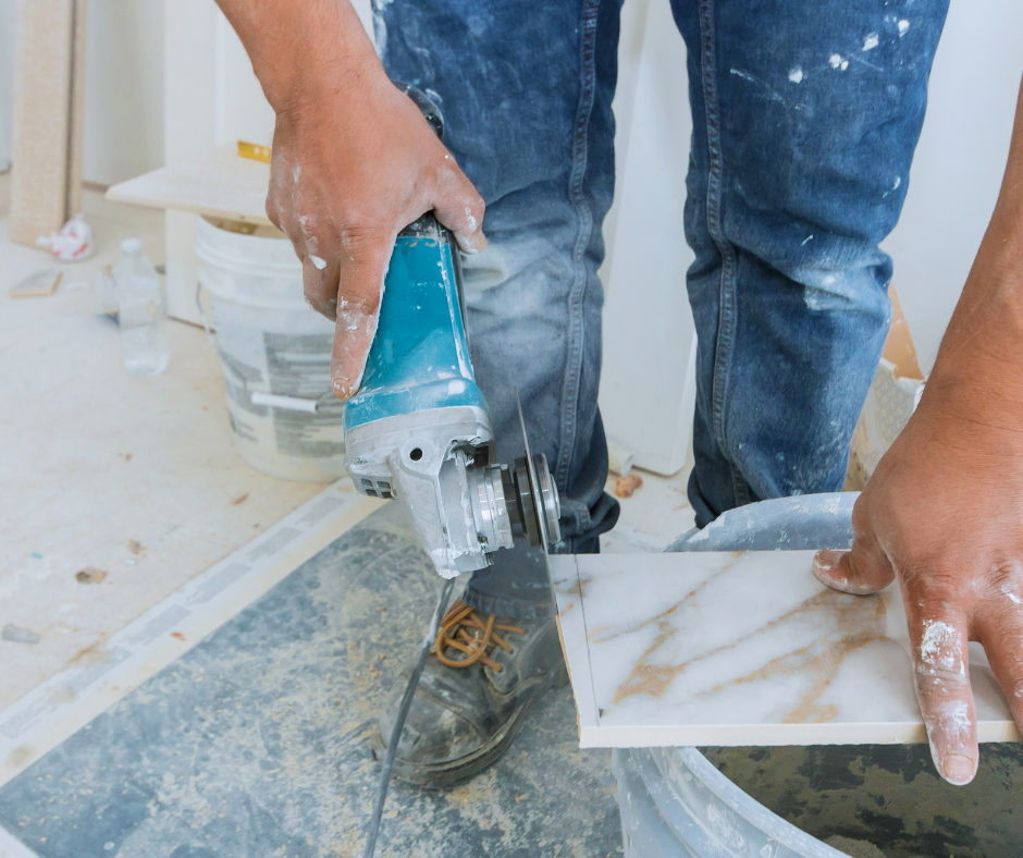 A man is cutting a tile with a grinder.