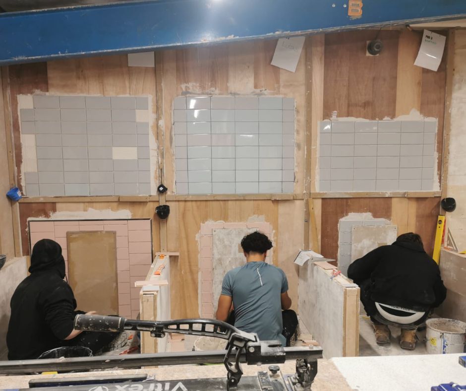 Students practising wall and floor tiling techniques during hands-on training at Chameleon School
