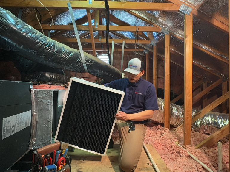 a man is working on an air conditioner in an attic .