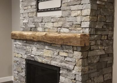 A stone fireplace with a wooden mantle in a living room