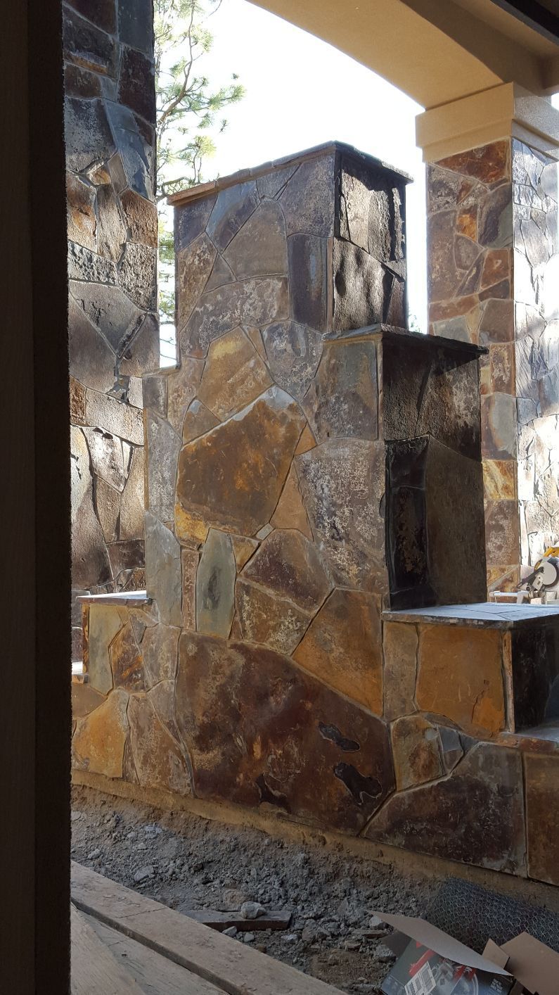 A stone fireplace is being built in the backyard of a house