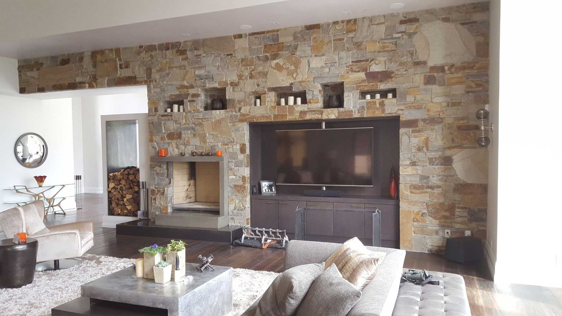 A living room with a stone wall and a flat screen tv