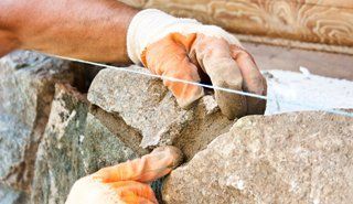  A workman fixing the grout on a stone wall