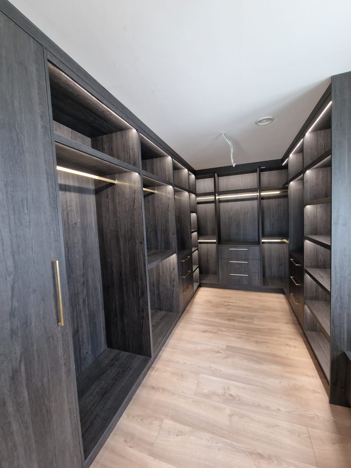 A large walk in closet with lots of shelves and cabinets.