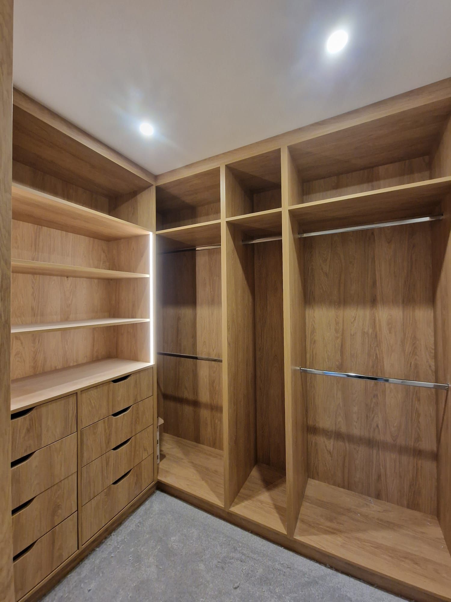 A walk in closet with lots of wooden shelves and drawers.