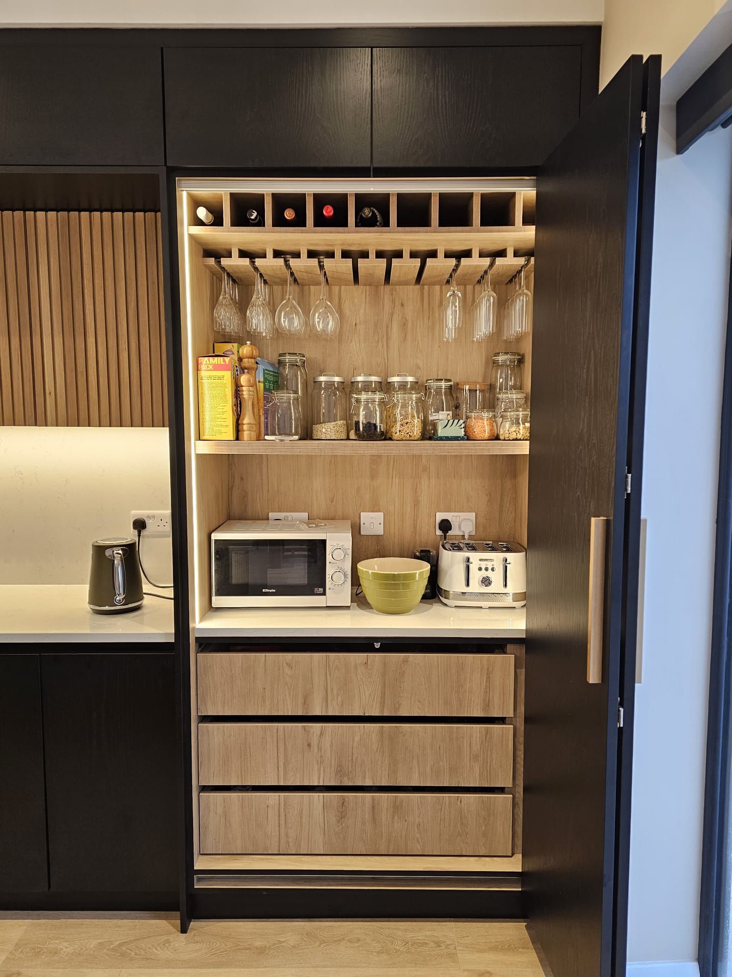 A kitchen with a wine rack , a microwave , and a toaster oven.