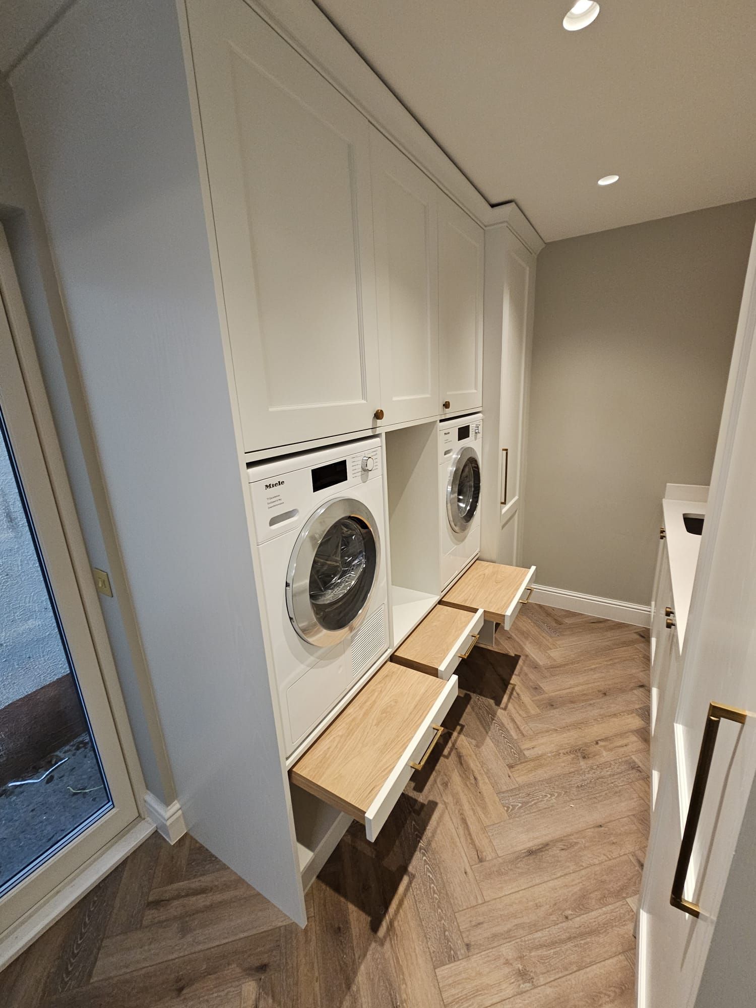 A laundry room with a washer and dryer and a wooden bench.