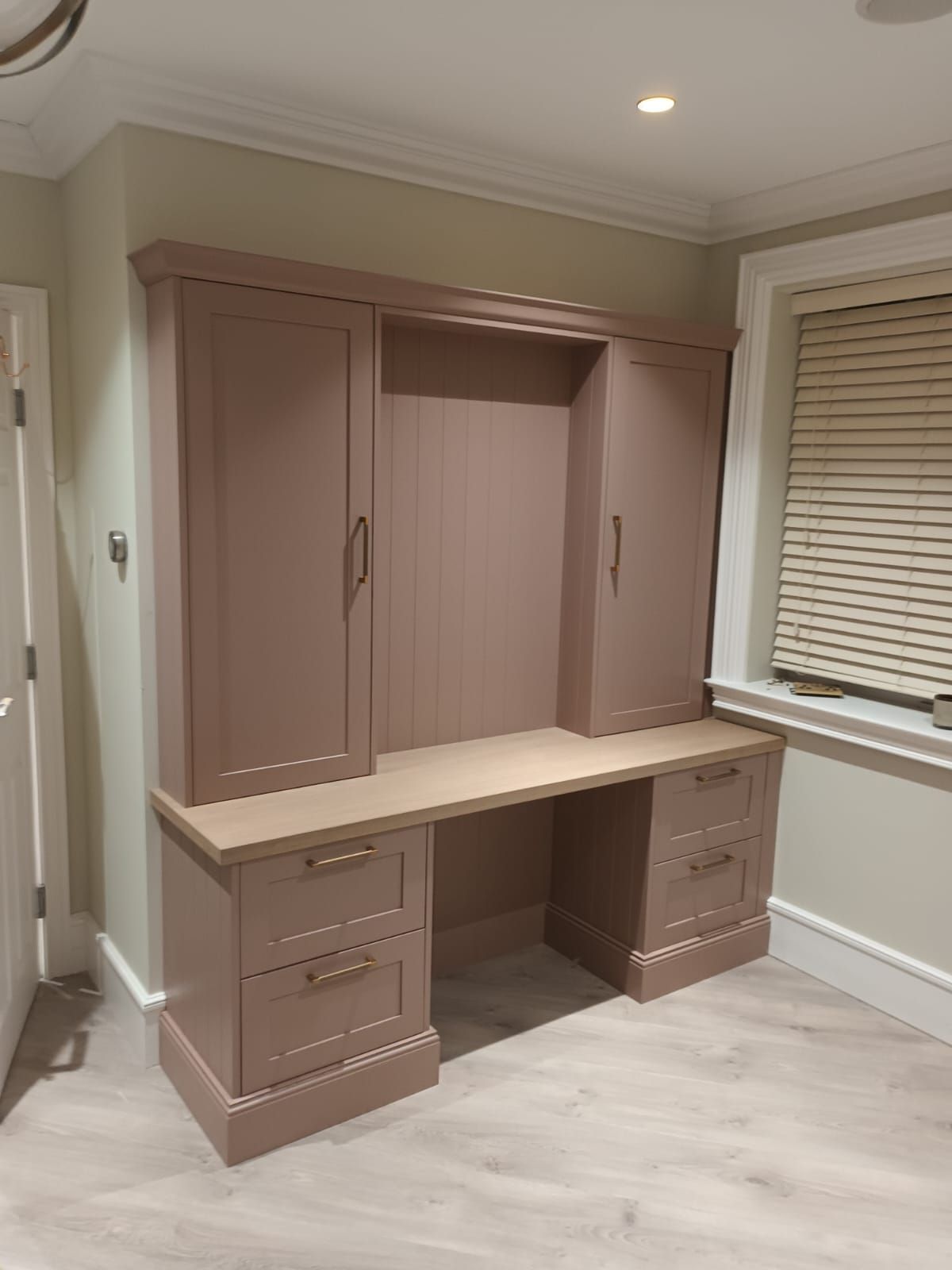 A room with a desk , cabinets , drawers and a window.