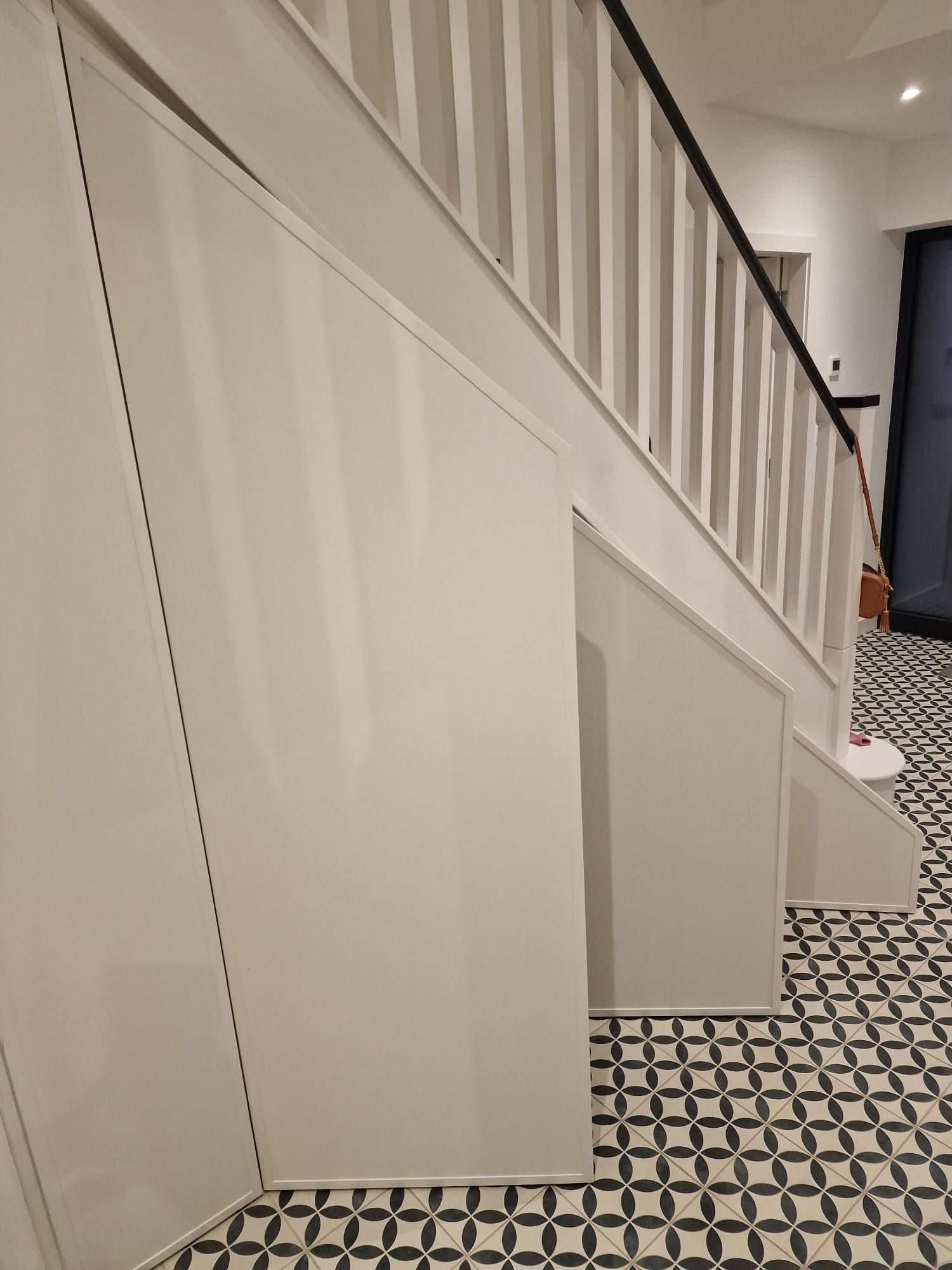 A white staircase with a black railing and a black and white tile floor.