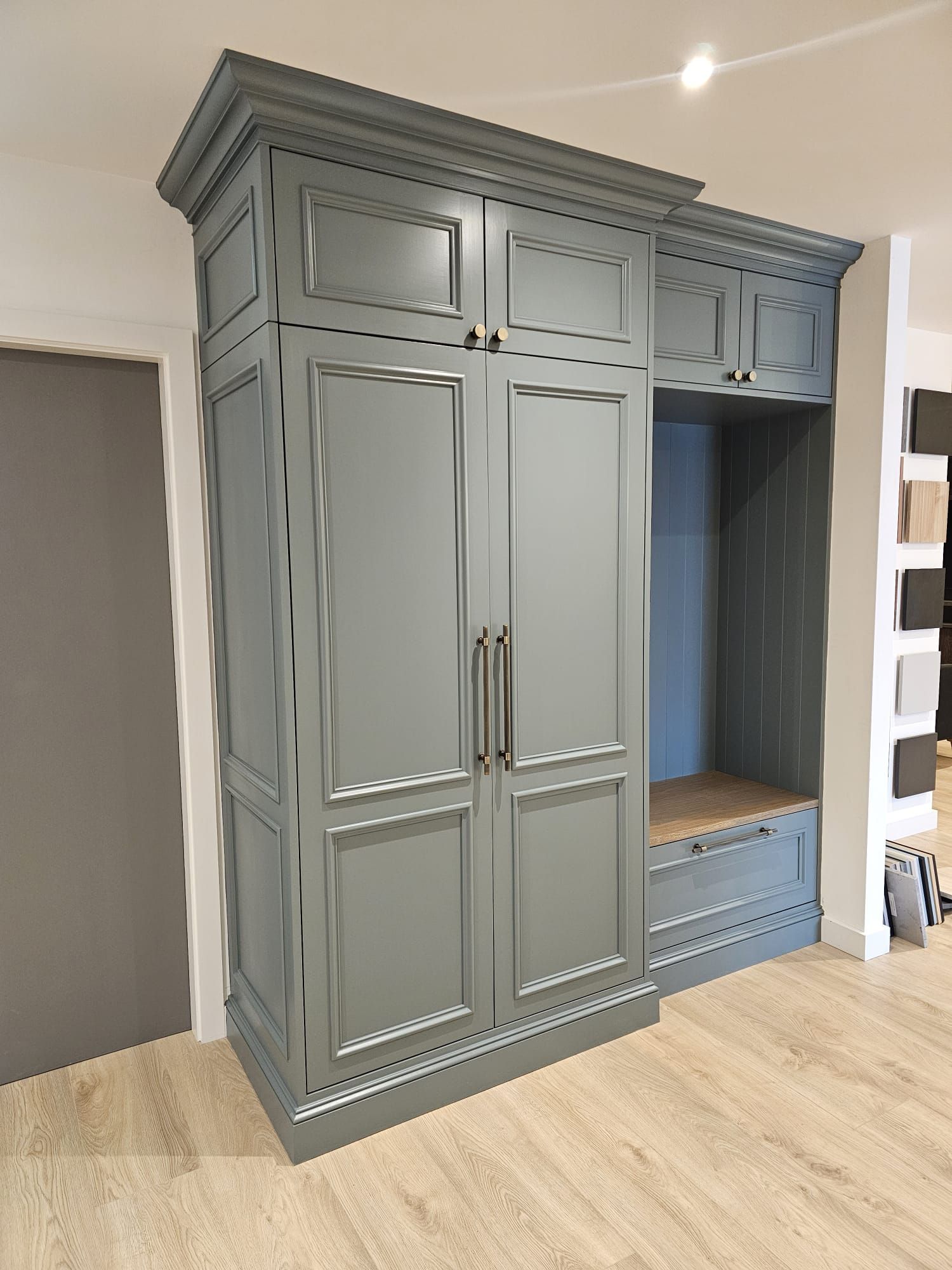 A large gray cabinet is sitting in a hallway next to a door.