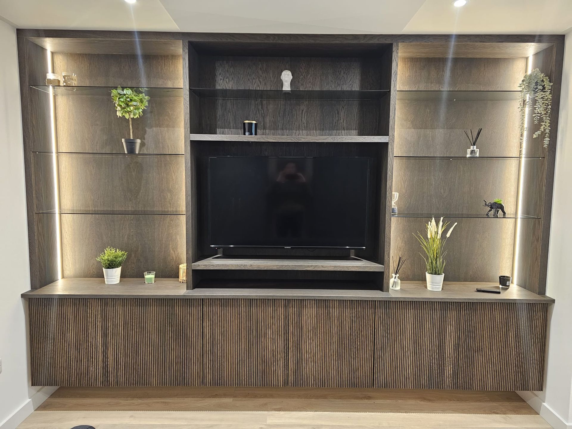 A large entertainment center with a flat screen tv and shelves.