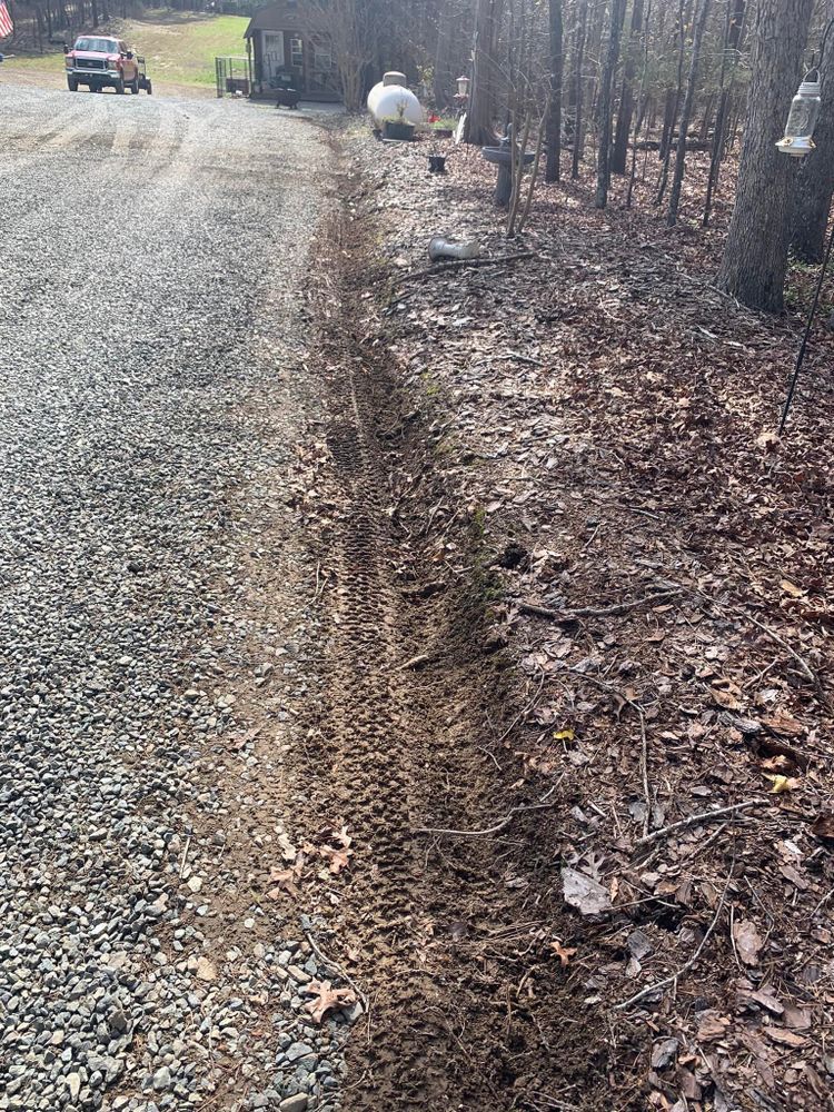 Gravel driveway with muddy tire tracks alongside a dirt path. A truck is visible in the distance.