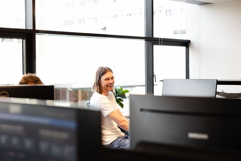 En mand sidder ved et skrivebord foran en computer på et kontor.