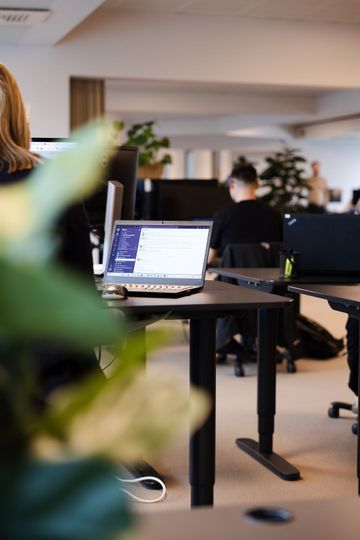 En kvinde sidder ved et skrivebord med en bærbar computer på.