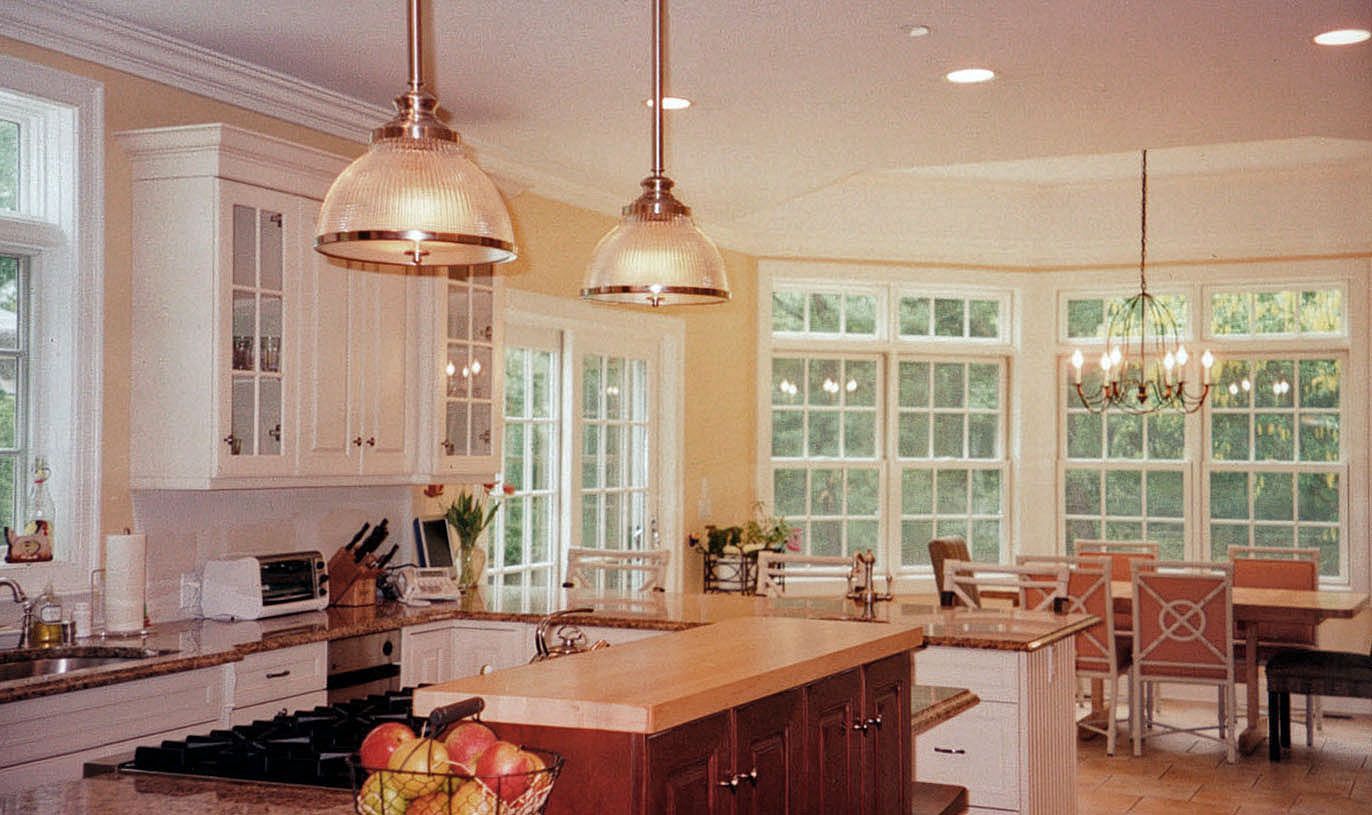 Kitchen with white cabinets, wood island, large windows, and pendant lights.