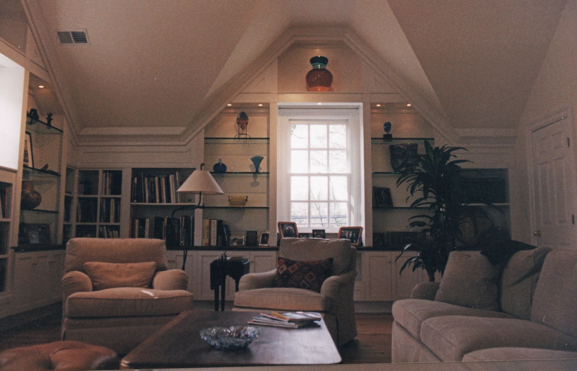 Cozy living room with built-in shelves, a window, and comfortable seating around a coffee table.