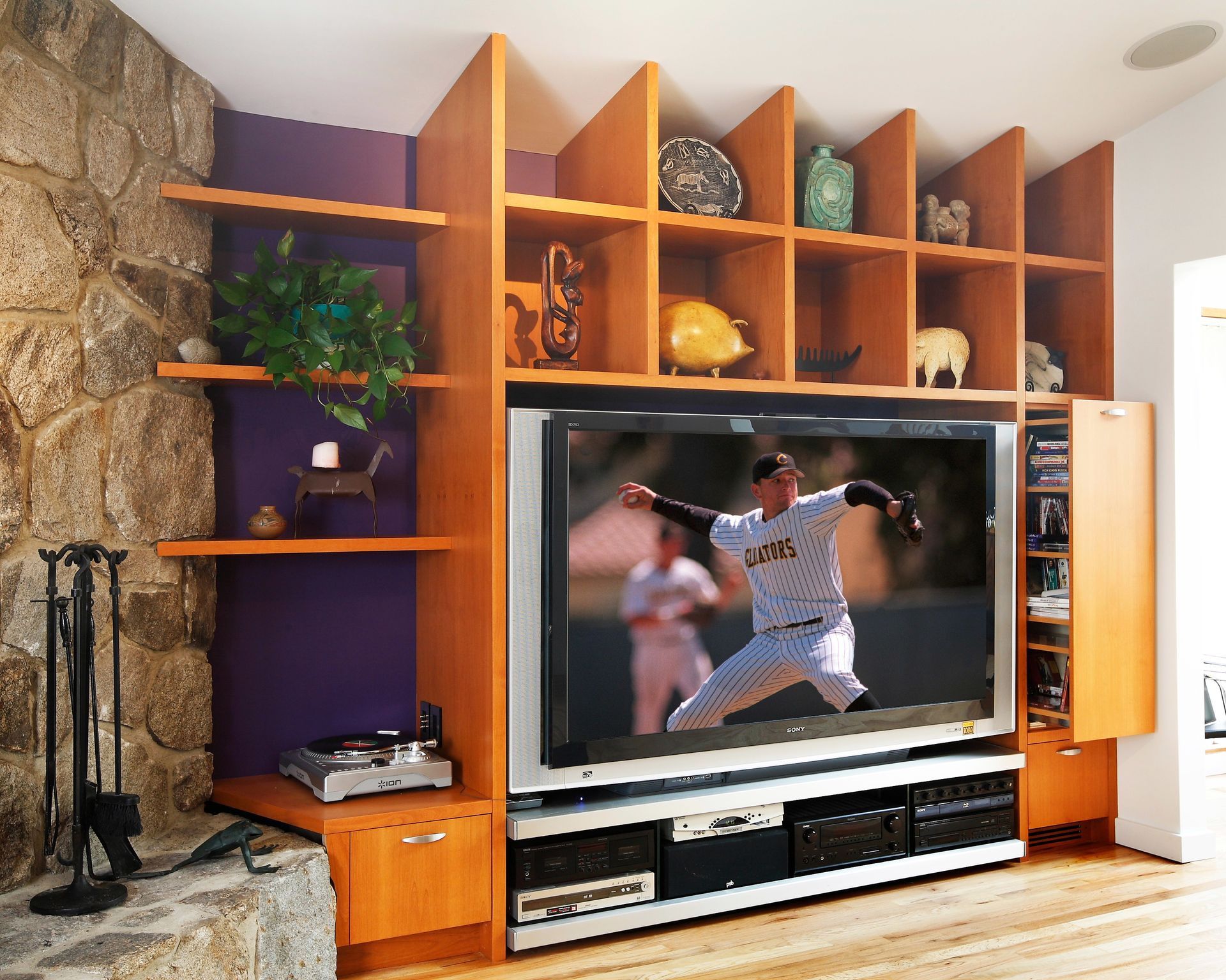 Built-in wooden shelving unit around a TV, displaying decorative items. A baseball game is on the screen.