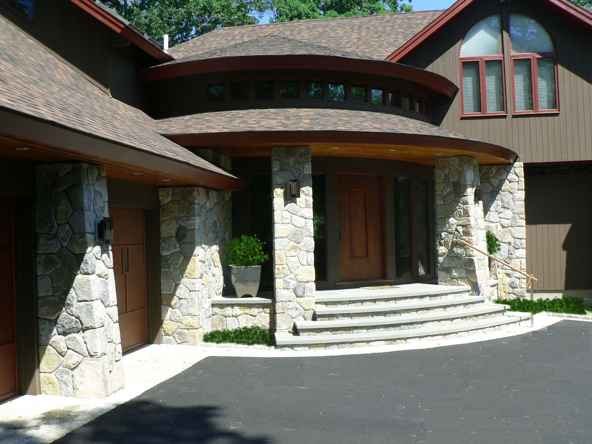 Stone and brown house exterior with circular entry, steps, and garage.
