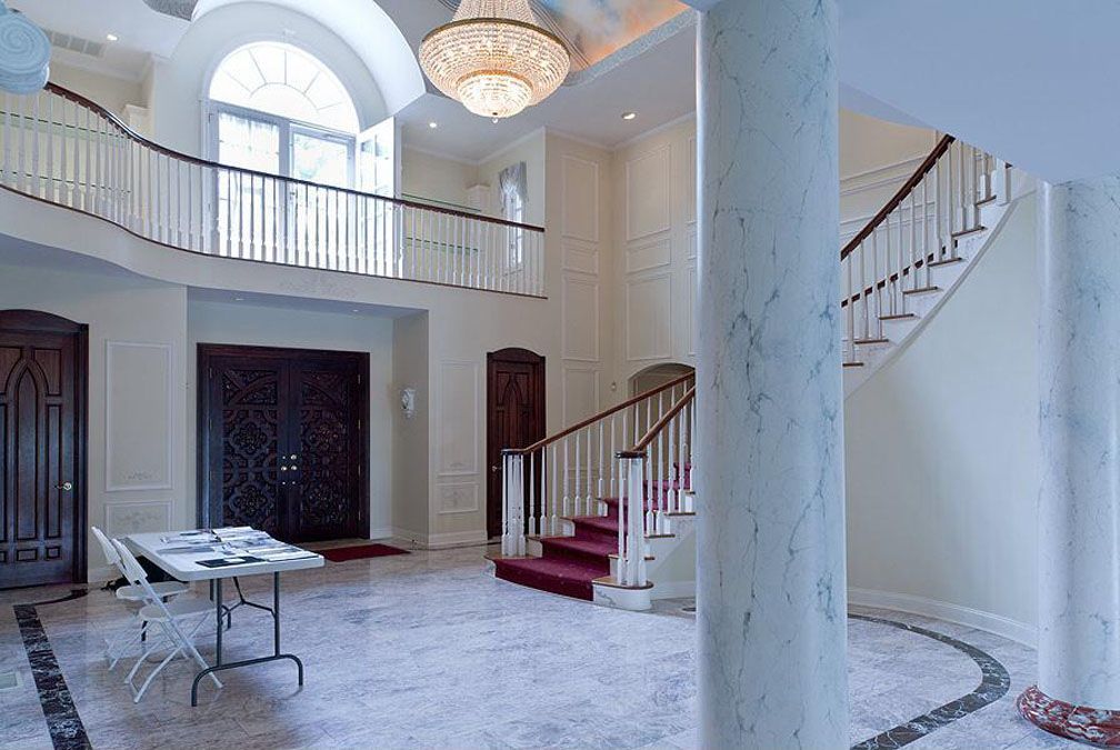 Grand, bright foyer with marble floor, staircase, and chandelier.