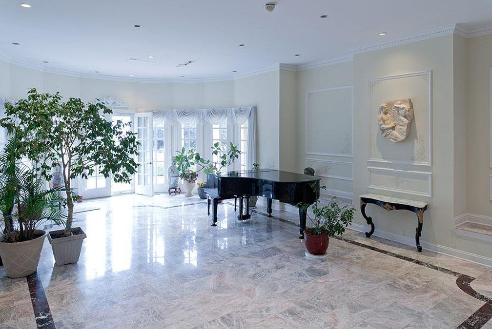 Spacious, elegant room with grand piano, marble floor, and potted plants.