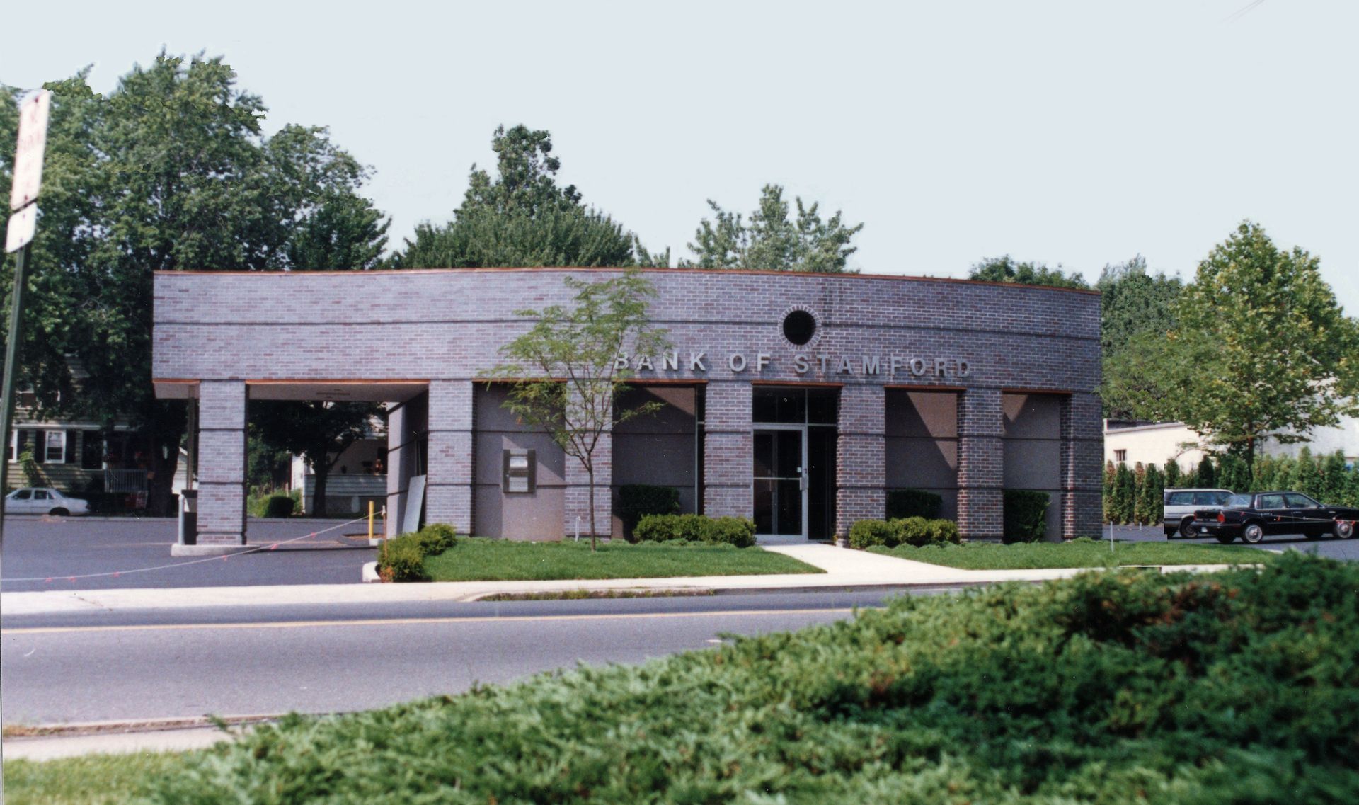Bank building with gray brick facade, drive-thru, and entrance door.